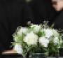 family at funeral in front of casket with bouquet of flowers